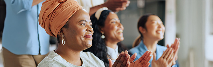 Three smiling women sitting next to each other clapping