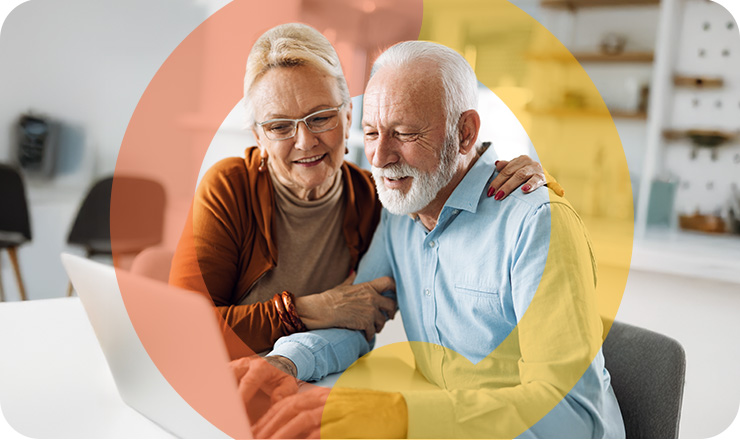Smiling older couple using a laptop together at a table Smiling older couple using a laptop together at a table