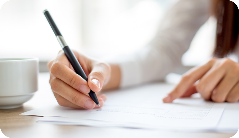 Person signing document on table next to coffee cup Person signing document on table next to coffee cup